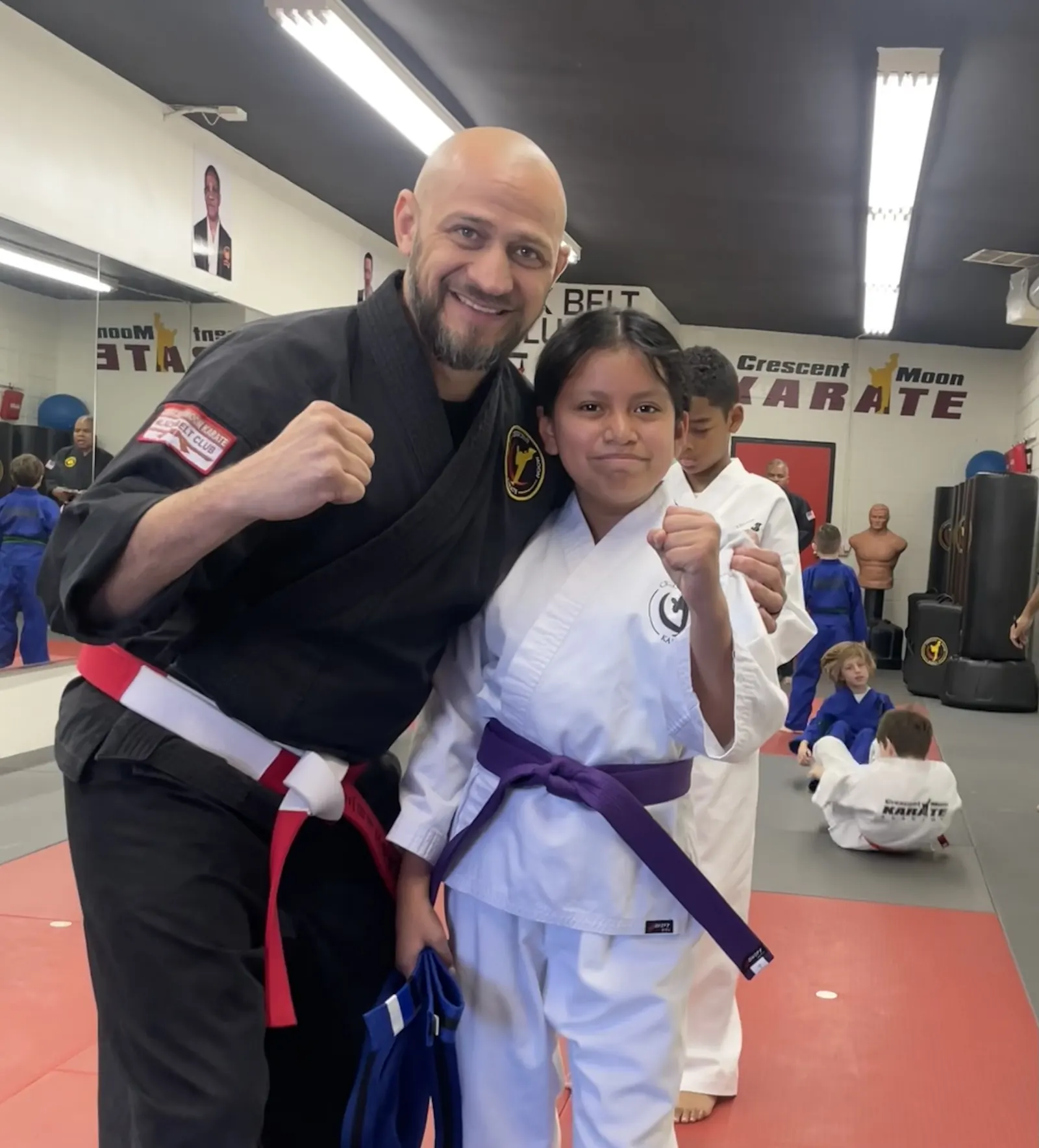 Hanshi Robert Torres stands beside a smiling young student